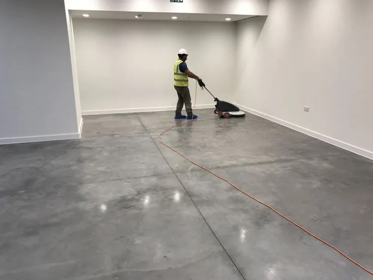 Operator diamond-grinding a concrete slab before coating