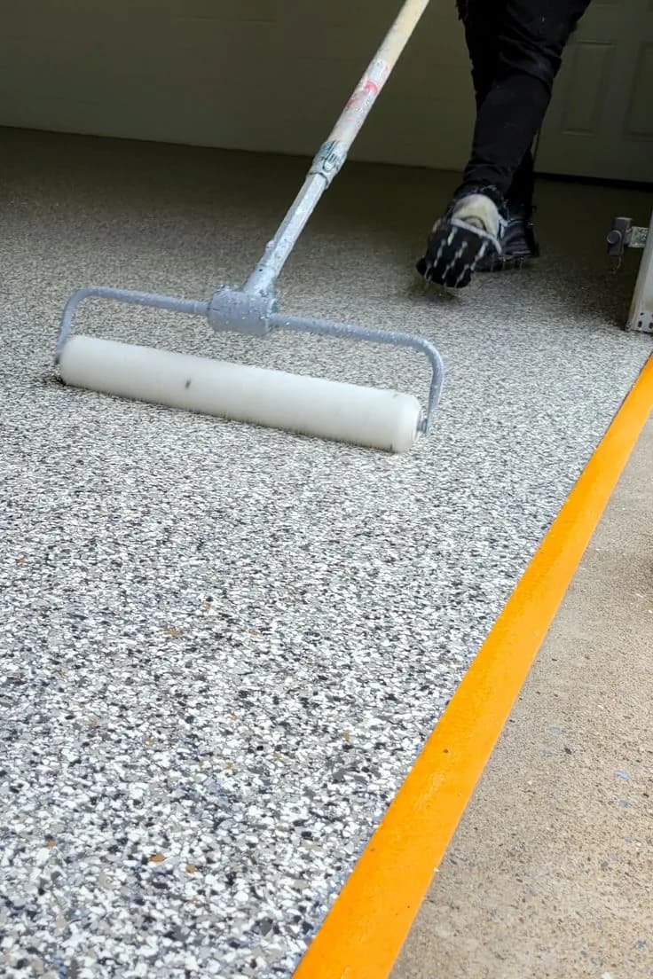 Installer rolling epoxy resin onto a prepared concrete floor