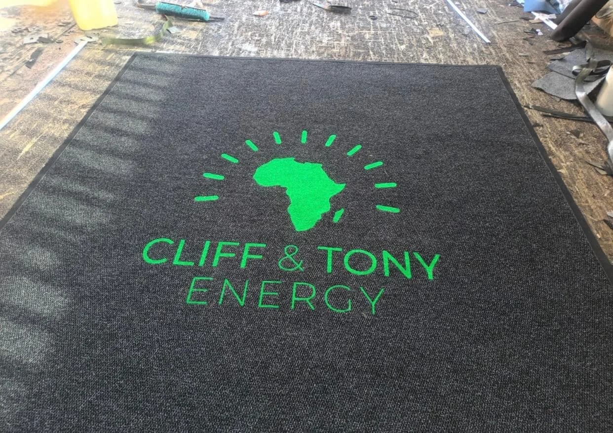 Branded mat with a green Africa-shaped logo on charcoal pile