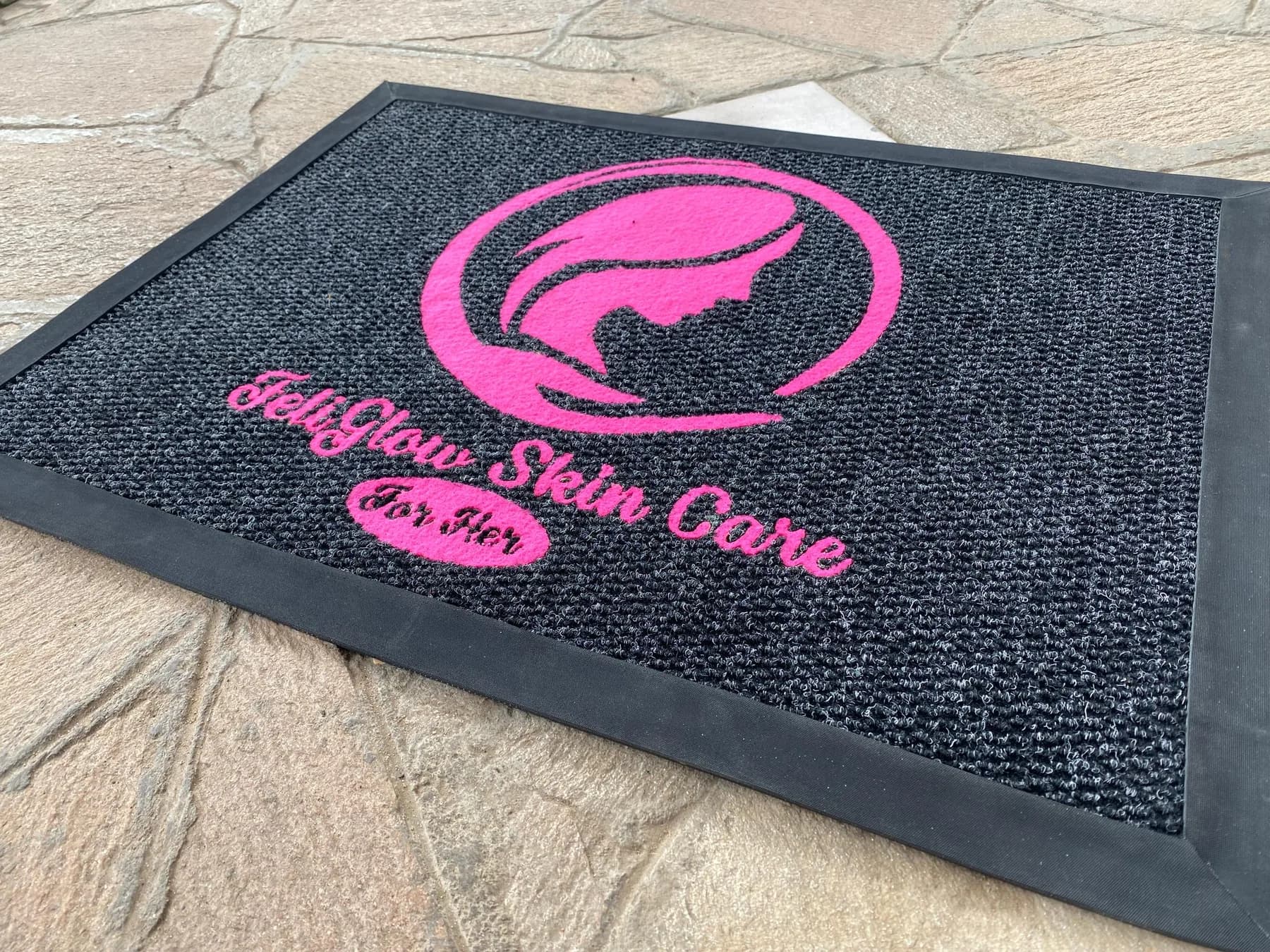 Branded mat with a pink logo on a rubber-edged scraper base