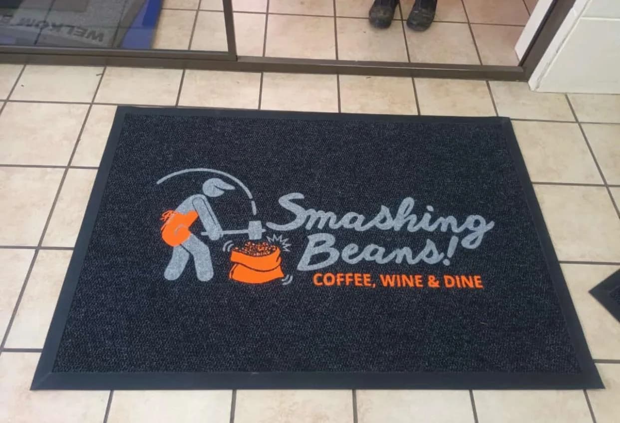 Charcoal branded mat with a full-colour coffee-brand logo