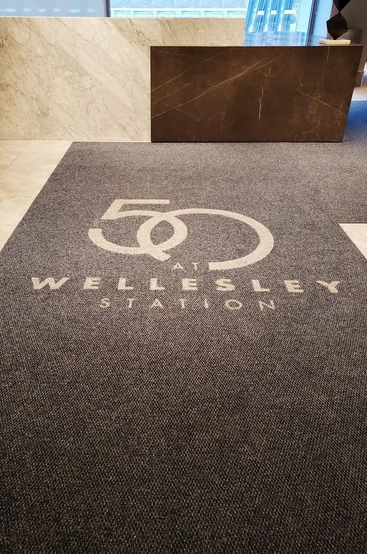 Dark commercial entrance mat with a subtle logo