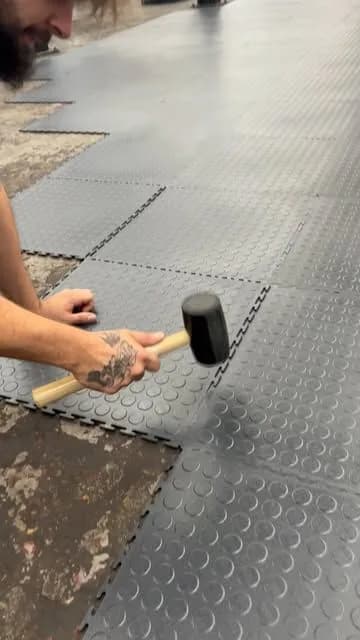Installer tapping a rubber tile into place with a mallet