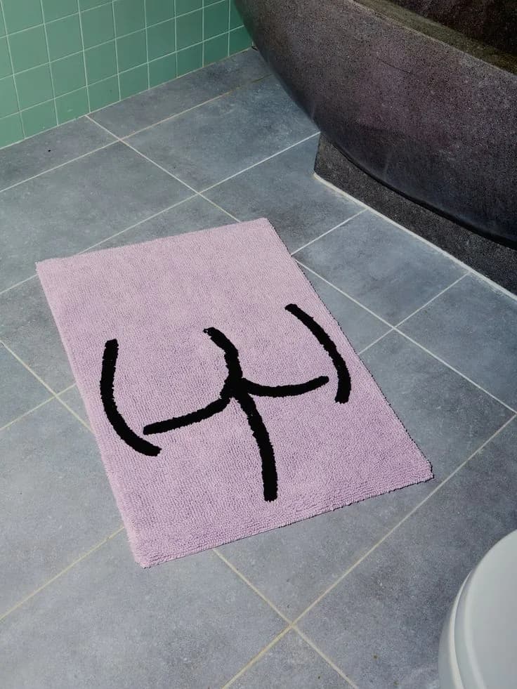 Soft pink tufted bath mat beside a bathtub