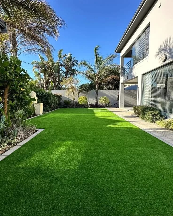 Artificial lawn beside a modern house and palm trees