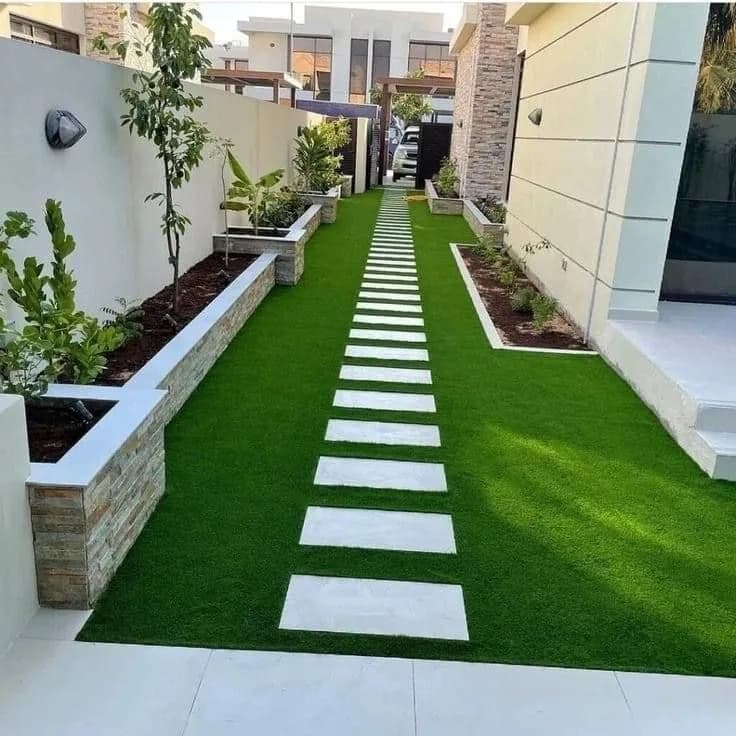 Narrow turf walkway between white walls with inset pavers
