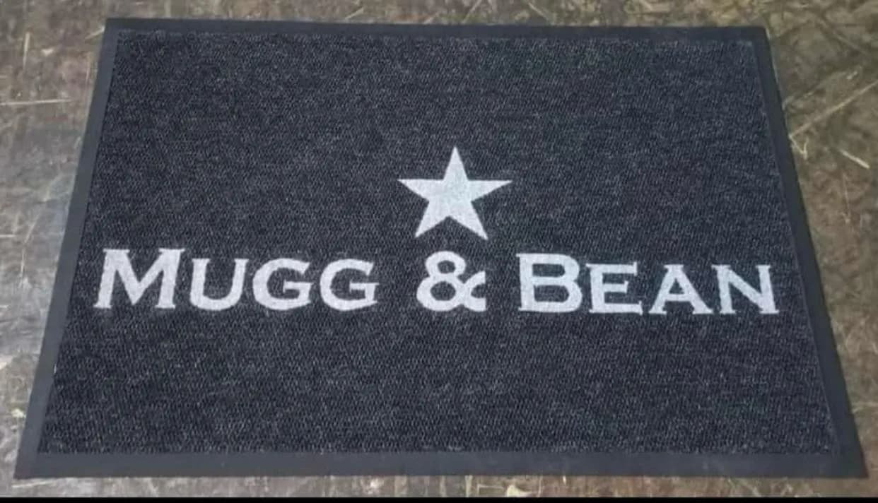 Charcoal branded entrance mat with a printed logo at a doorway